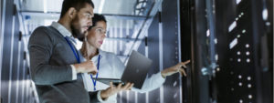 Man holding a laptop and standing with a woman in a server room